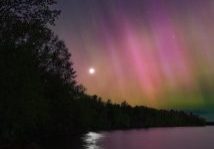 a purple and green aurora bore over a body of water